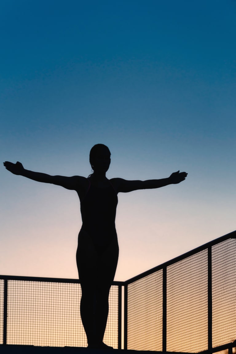 Silhouette d'une nageuse sur un plongeoir prête pour un entraînement de natation et de plongeon