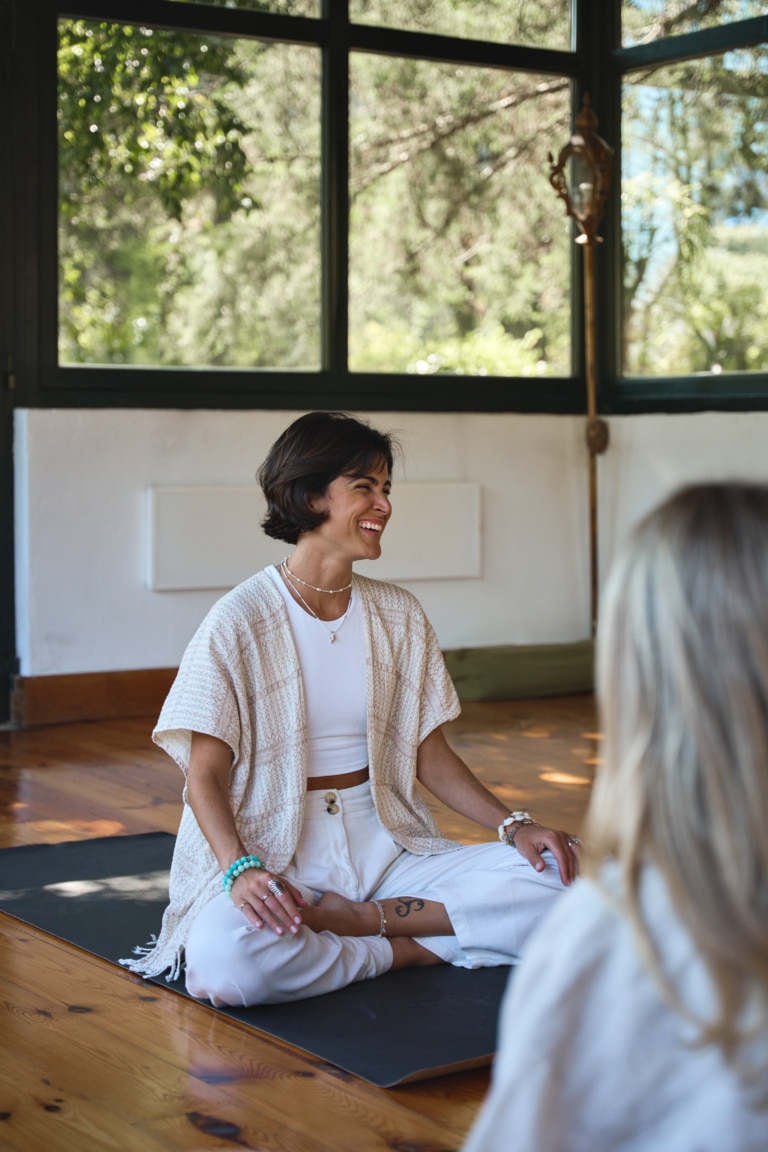 Femme souriante en séance de yoga et méditation lors d'une retraite de bien-être dans un studio lumineux