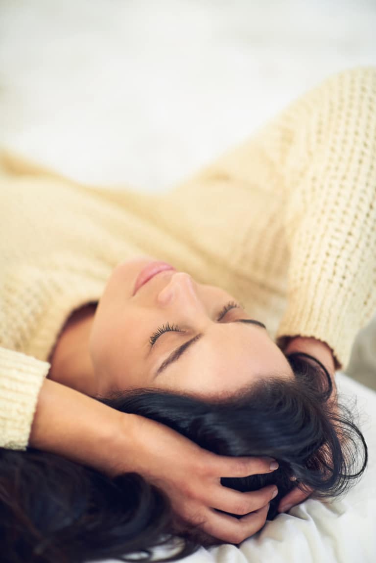 Femme détendue allongée les yeux fermés pour une séance de relaxation, de sophrologie et de bien-être
